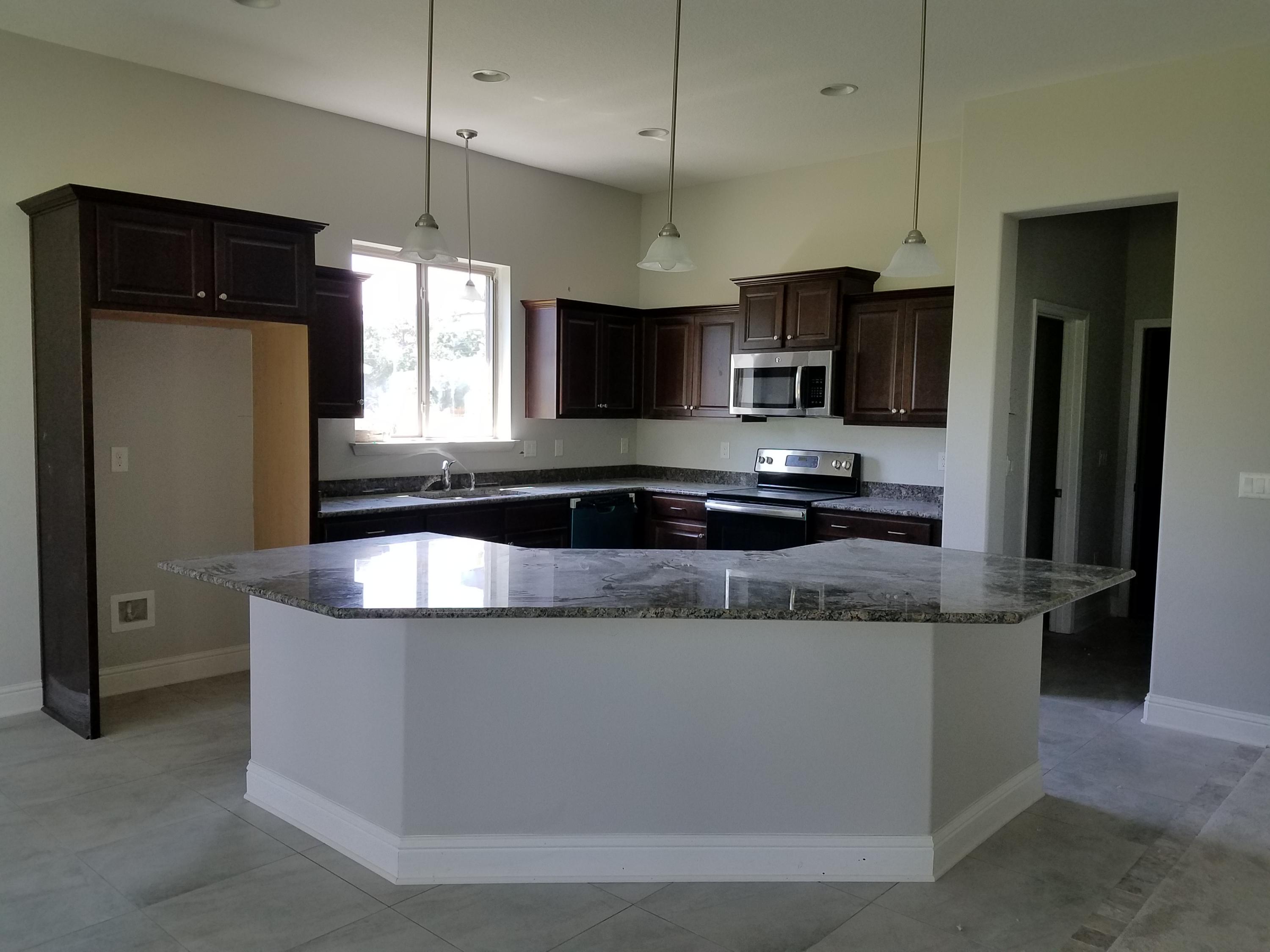 2399 Cove Road Navarre, FL 32566 - Photo 7 of 7 a large kitchen with stainless steel appliances granite countertop a sink a microwave and refrigerator