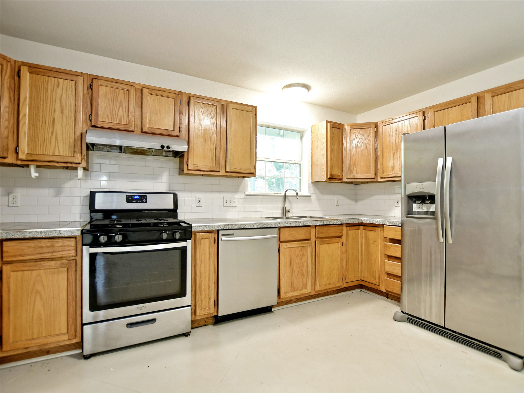 4604 Red River Street, Unit A Austin, TX 78751 - Photo 6 of 15 Kitchen featuring natural wood cabinetry, white subway tile backsplash, stainless steel appliances, and light-toned countertops