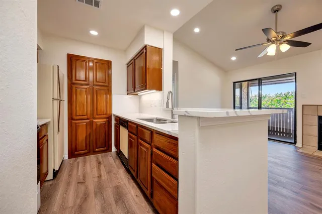 a kitchen with stainless steel appliances granite countertop a refrigerator a sink dishwasher a stove and a dining table with wooden floor