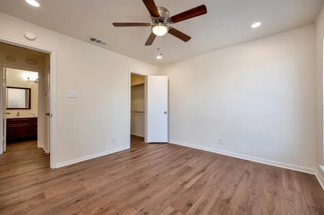 an empty room with wooden floor a ceiling fan and closet