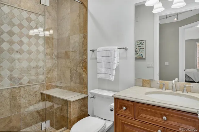 a bathroom with a granite countertop sink a toilet a mirror and shower