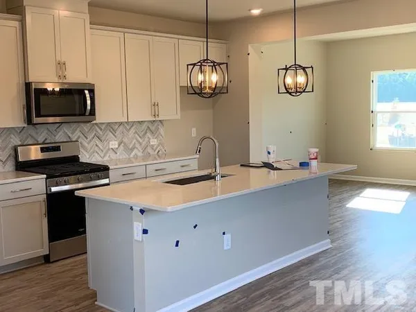 a kitchen with stainless steel appliances granite countertop a sink a stove and a wooden floors