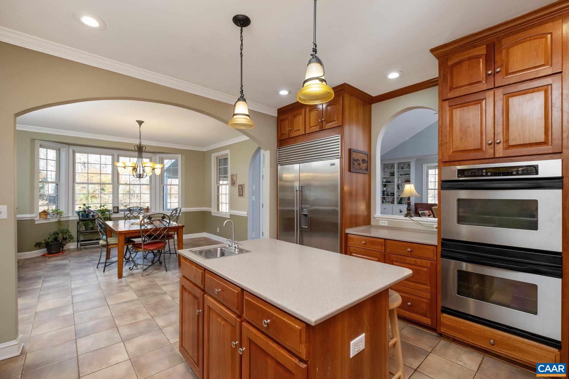 684 Campbell Road Keswick, VA 22947 - Photo 24 of 51 a large kitchen with kitchen island a stove a sink a dining table and chairs with wooden floor
