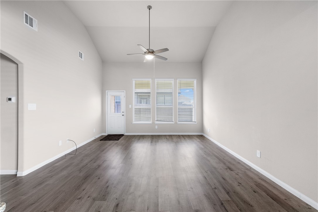 974 Harper Lane Bryan, TX 77803 - Photo 13 of 38 Unfurnished room featuring dark wood-style flooring, ceiling fan, and high vaulted ceiling
