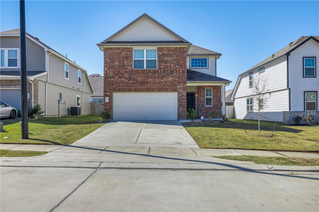974 Harper Lane Bryan, TX 77803 - Photo 4 of 38 Traditional-style home featuring a front lawn, driveway, brick siding, and an attached garage