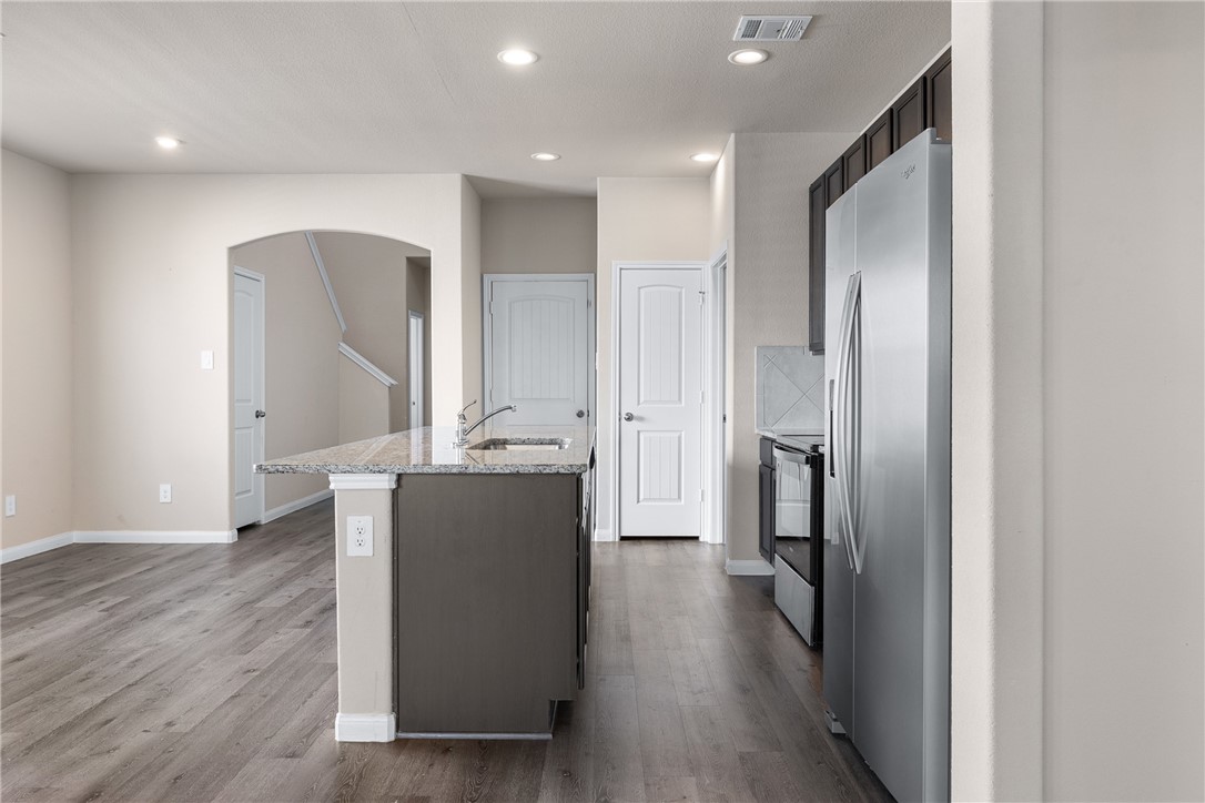 974 Harper Lane Bryan, TX 77803 - Photo 8 of 38 Kitchen featuring stainless steel fridge, an island with sink, recessed lighting, dark wood-type flooring, and arched walkways