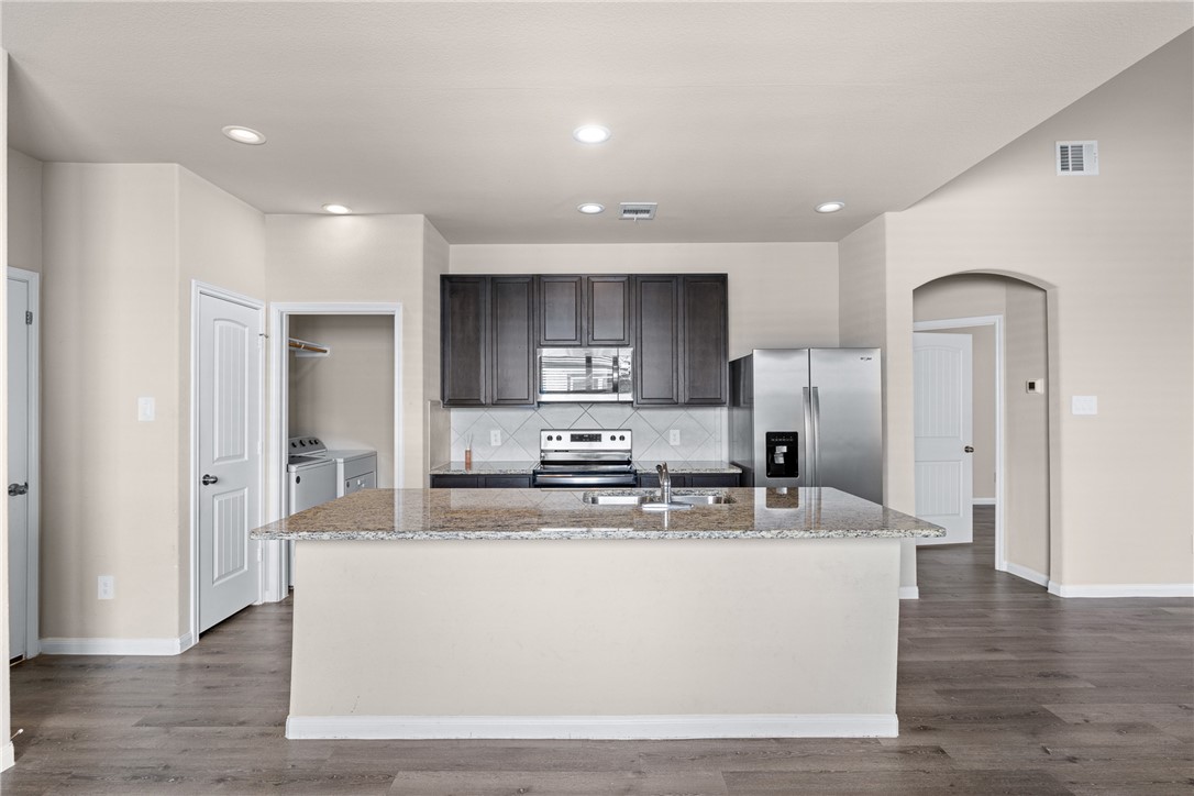 974 Harper Lane Bryan, TX 77803 - Photo 9 of 38 Kitchen with backsplash, appliances with stainless steel finishes, light wood-style floors, independent washer and dryer, and recessed lighting