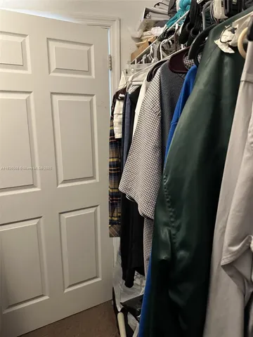a view of walk in closet with clothes and shoes