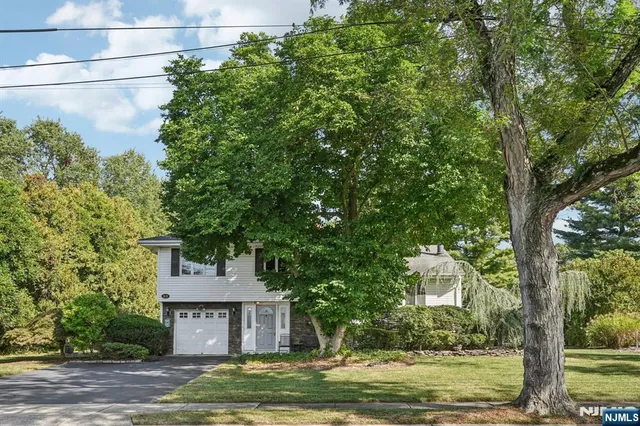 a front view of a house with a garden and trees