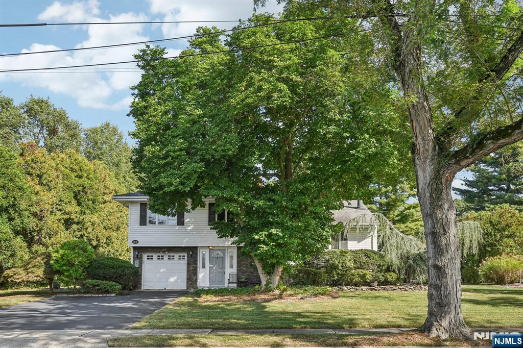 a front view of a house with a garden and trees
