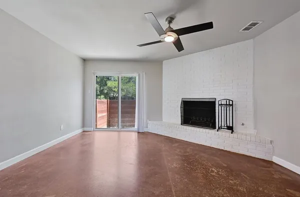 an empty room with windows and fireplace