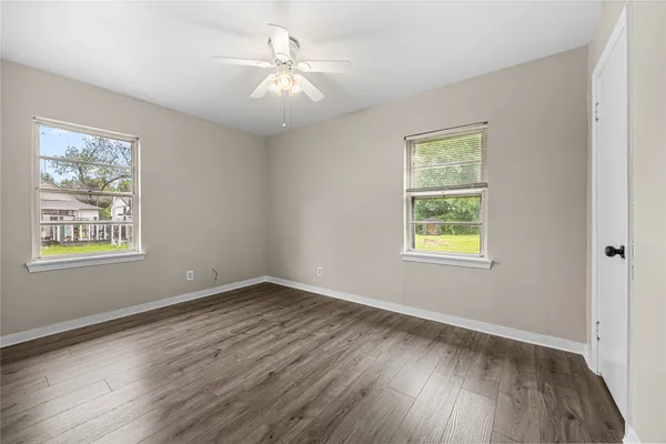 a view of an empty room with wooden floor and a window