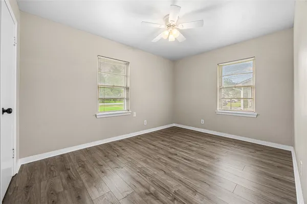 a view of an empty room with wooden floor and a window