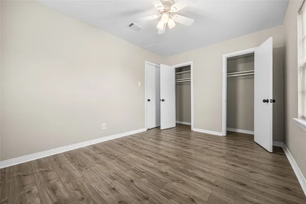 an empty room with wooden floor and closet area