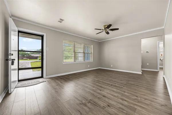 an empty room with wooden floor and windows