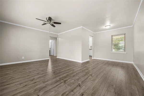 an empty room with wooden floor chandelier fan and windows