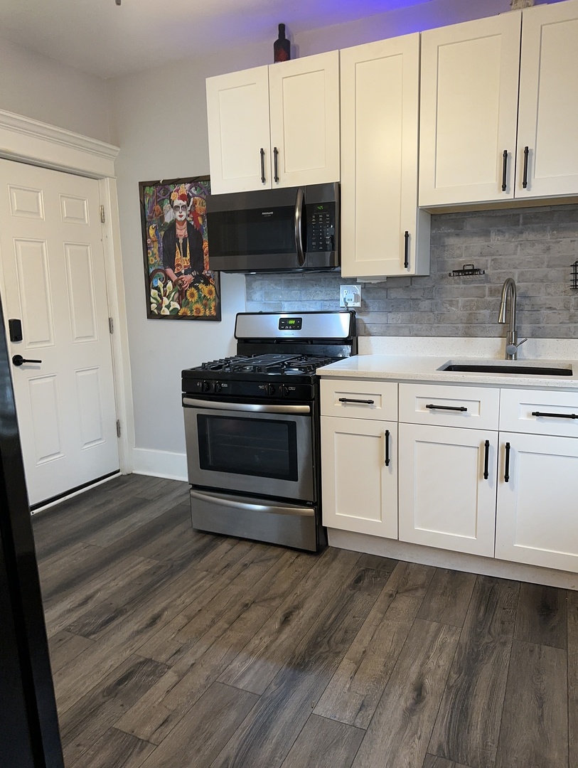 3062 South Lyman Street, Unit 2 Chicago, IL 60608 - Photo 2 of 7 a kitchen with stainless steel appliances a stove a sink and a microwave