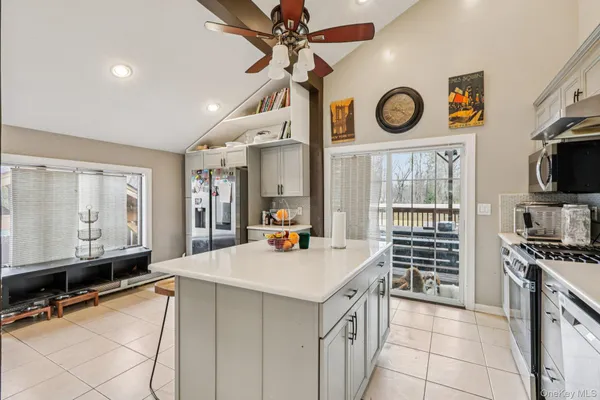 a kitchen with a stove a clock and a view of living room