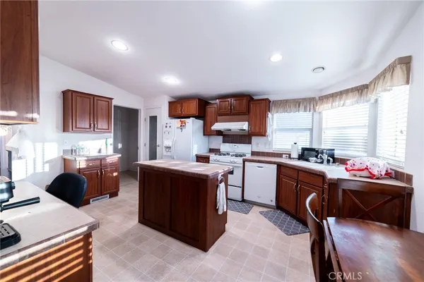 a kitchen with stainless steel appliances kitchen island granite countertop a sink dishwasher stove and refrigerator