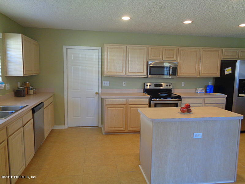 2444 Mallory Hills Road Jacksonville, FL 32221 - Photo 17 of 40 a kitchen with stainless steel appliances a stove a sink a refrigerator a center island and cabinets