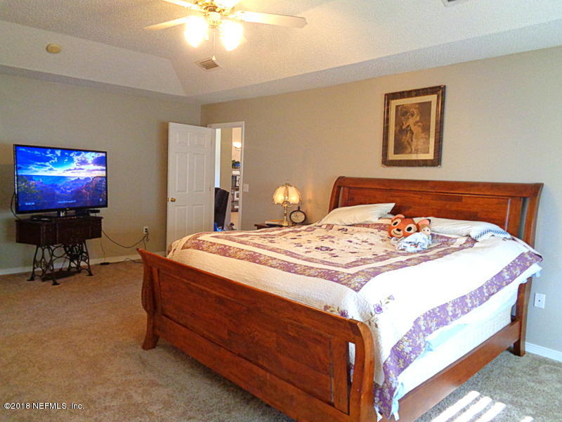 2444 Mallory Hills Road Jacksonville, FL 32221 - Photo 20 of 40 a bedroom with a bed and a chandelier