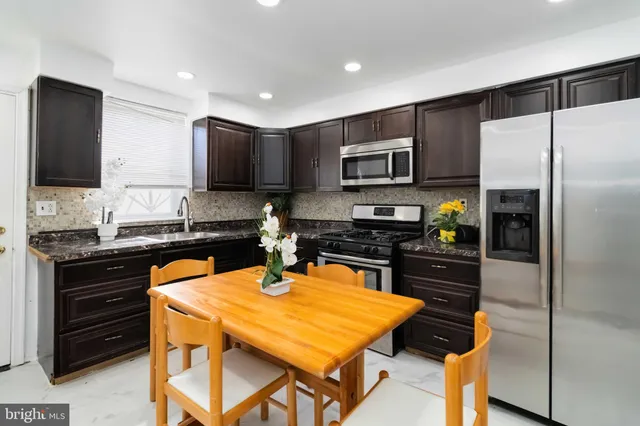 a kitchen with a refrigerator a stove a sink a dining table and chairs