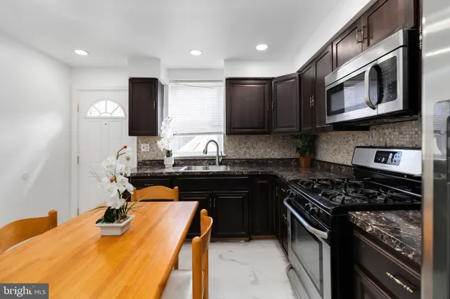 a kitchen with stainless steel appliances granite countertop a stove a sink and a microwave