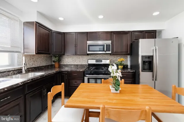 a kitchen with stainless steel appliances granite countertop a stove refrigerator a sink dishwasher a dining table and chairs