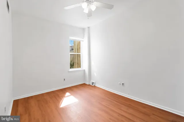 an empty room with a chandelier fan and windows