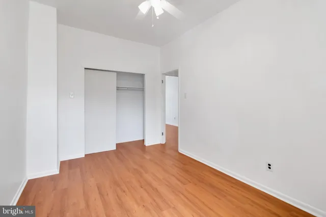 an empty room with wooden floor and fan