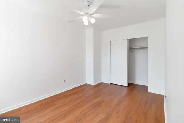an empty room with wooden floor and fan