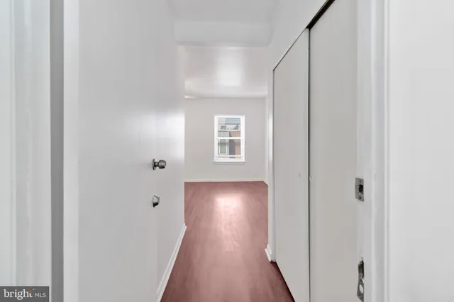 a view of a hallway with wooden floor and closet
