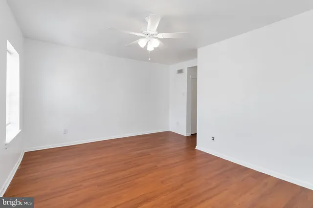 an empty room with wooden floor and fan
