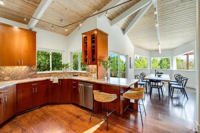 a dining hall with stainless steel appliances granite countertop a dining table chairs and a sink