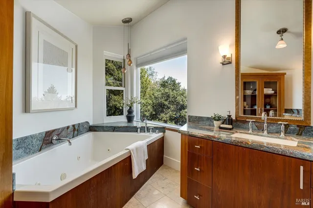 a bathroom with a granite countertop tub sink and mirror