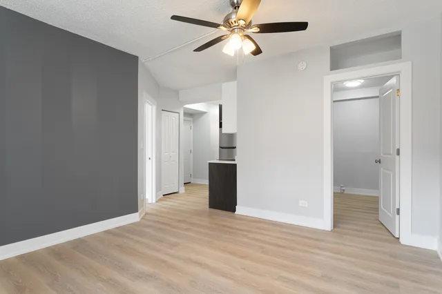 a view of a room with wooden floor and a ceiling fan