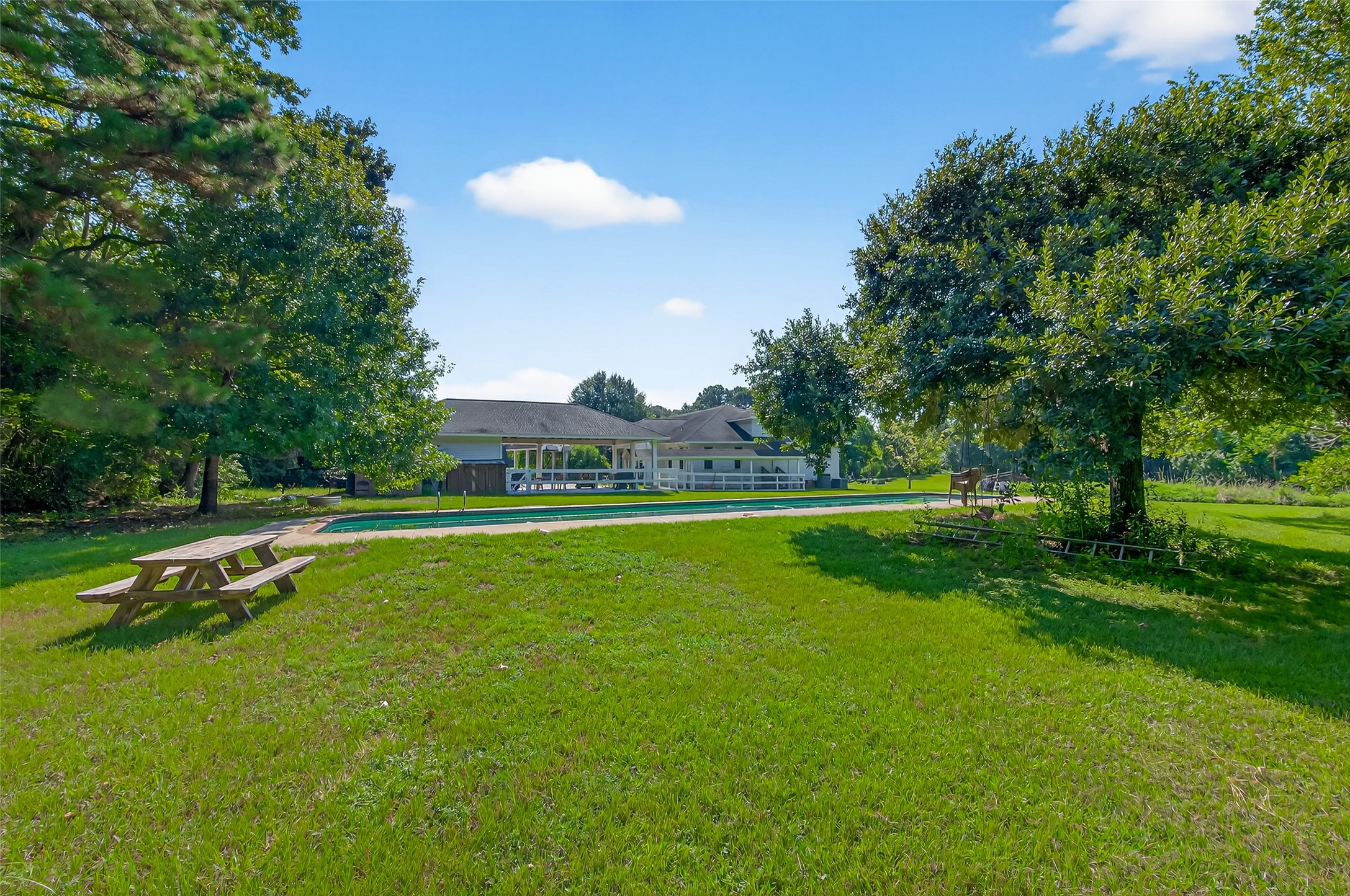 38011 Spur 149 Road Magnolia, TX 77354 - Photo 47 of 49 Spacious backyard with lush greenery, a swimming pool, and a picnic area, perfect for outdoor relaxation and gatherings.