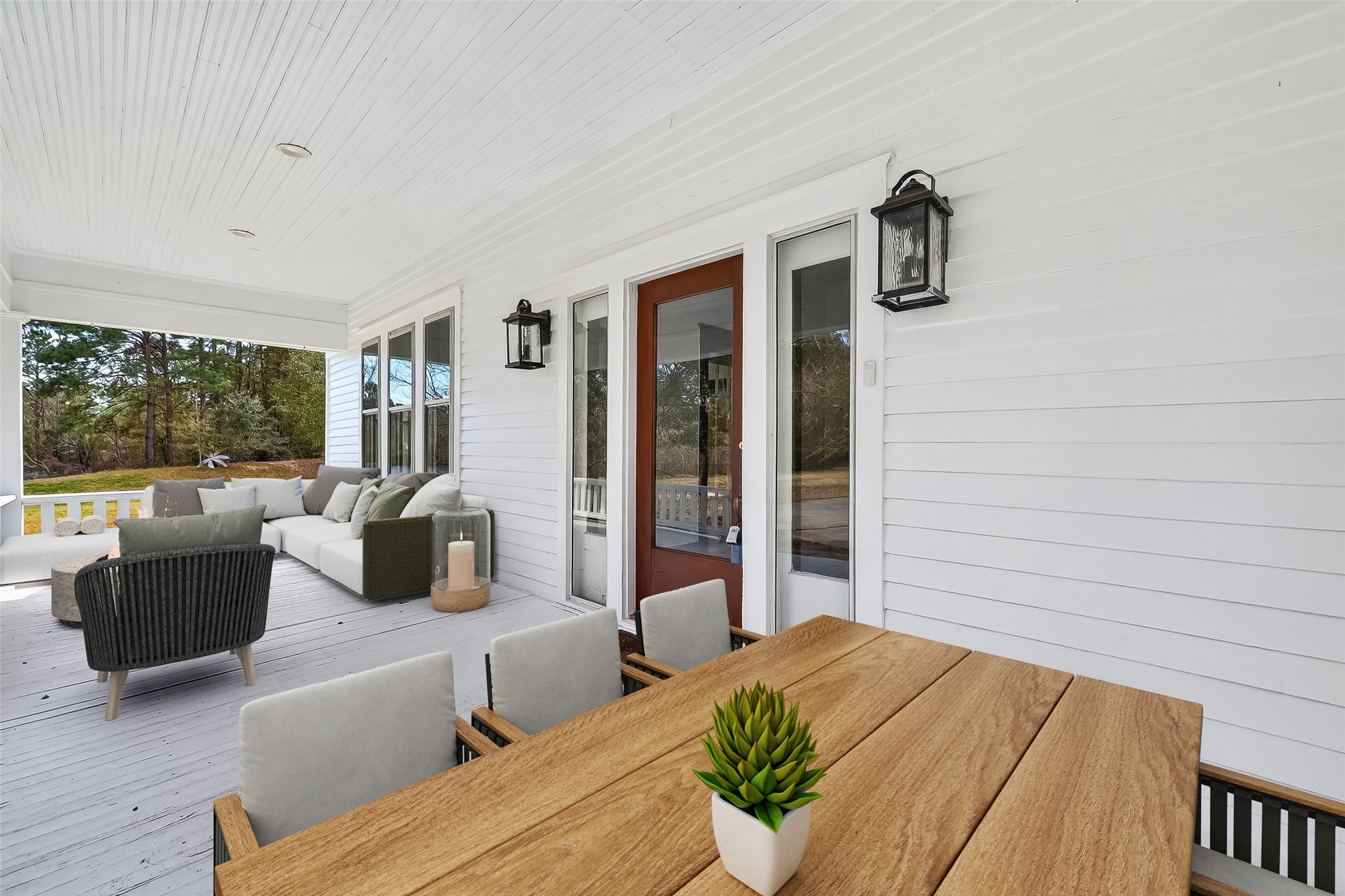 38011 Spur 149 Road Magnolia, TX 77354 - Photo 6 of 40 This inviting porch features a cozy seating area with a sofa and chairs, complemented by a wooden dining table. It's enhanced by stylish lanterns and surrounded by serene greenery, making it perfect for relaxation and outdoor gatherings.