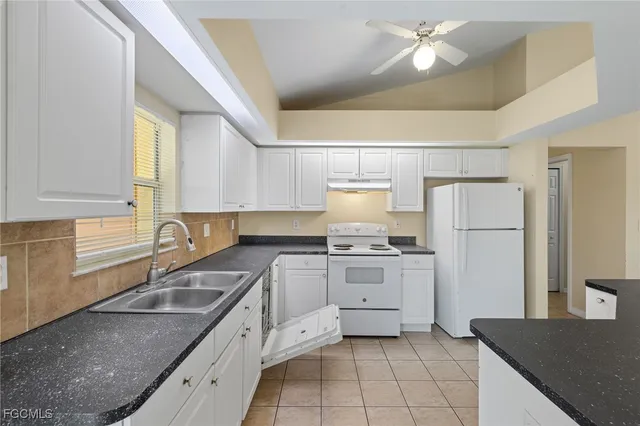 a kitchen with stainless steel appliances granite countertop a sink stove refrigerator and cabinets