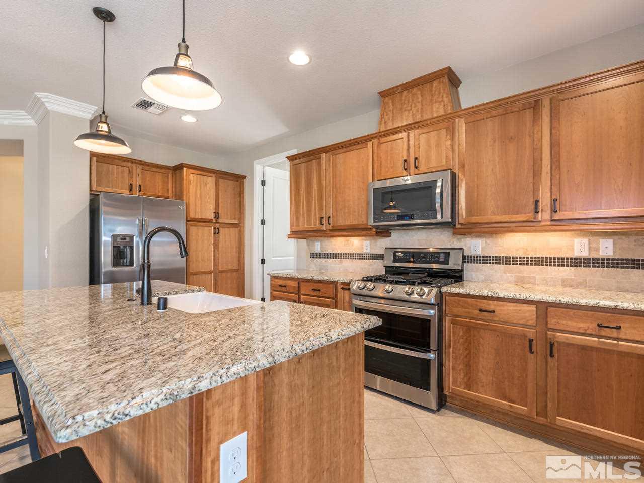 2180 Arpagos Lane Reno, NV 89521 - Photo 6 of 25 a kitchen with granite countertop a stove top oven microwave and cabinets