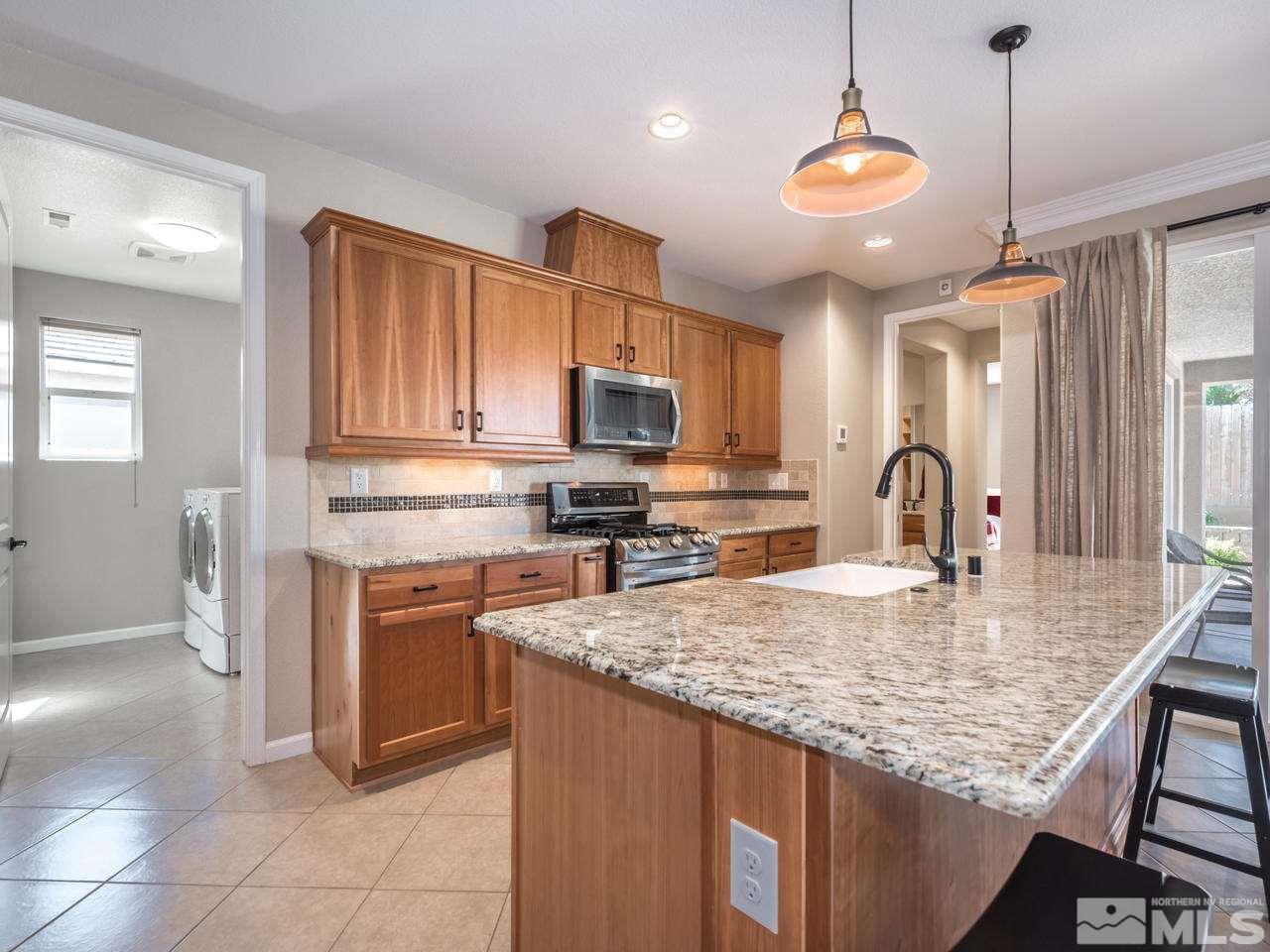 2180 Arpagos Lane Reno, NV 89521 - Photo 9 of 25 a kitchen with kitchen island granite countertop a stove oven and a sink with granite countertops