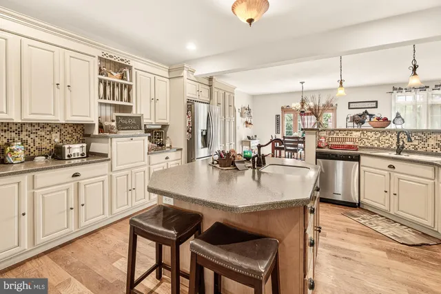 a kitchen with stainless steel appliances granite countertop a sink dishwasher stove and white cabinets with wooden floor