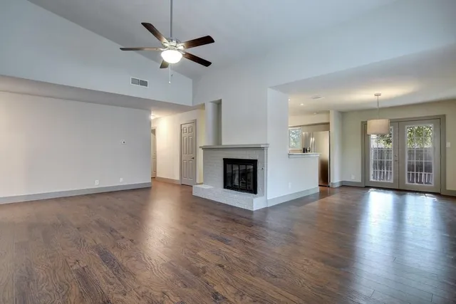 a view of an empty room with wooden floor and a fireplace