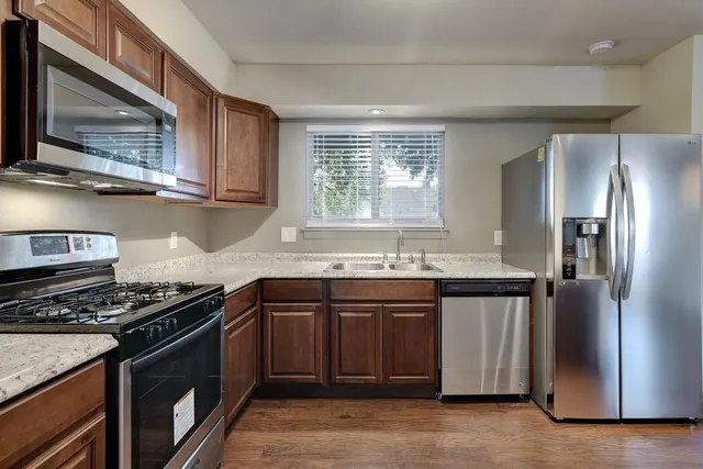 a kitchen with stainless steel appliances granite countertop a sink stove and refrigerator