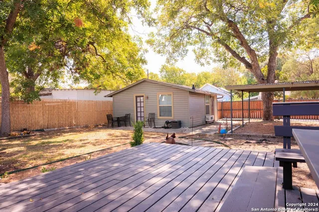 a backyard of a house with table and chairs under an umbrella