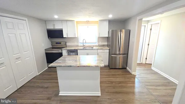 a kitchen with stainless steel appliances white cabinets and a stove top oven