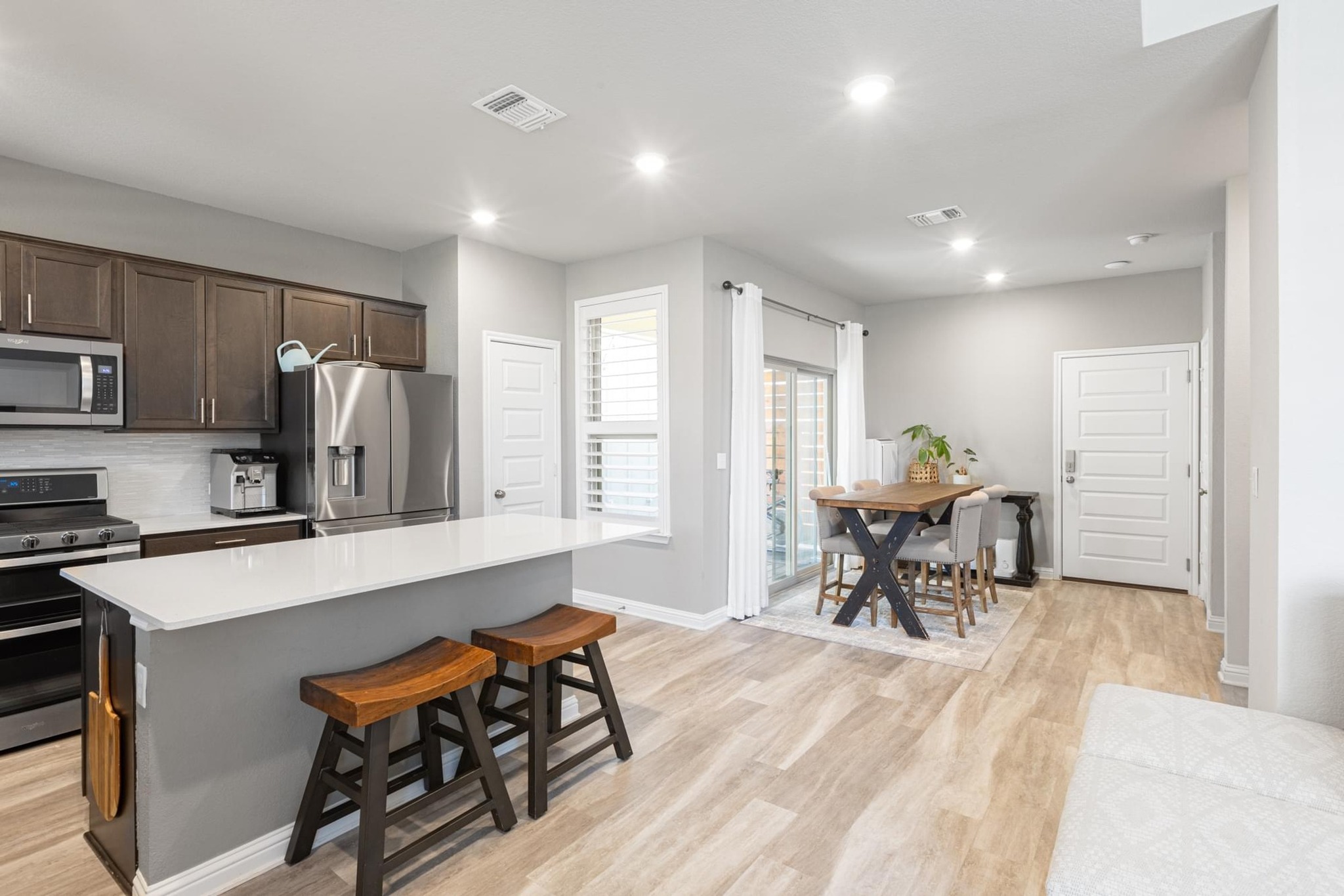 7801 Frida Bend Austin, TX 78744 - Photo 5 of 26 A contemporary kitchen and dining space feature stainless steel appliances and durable flooring.