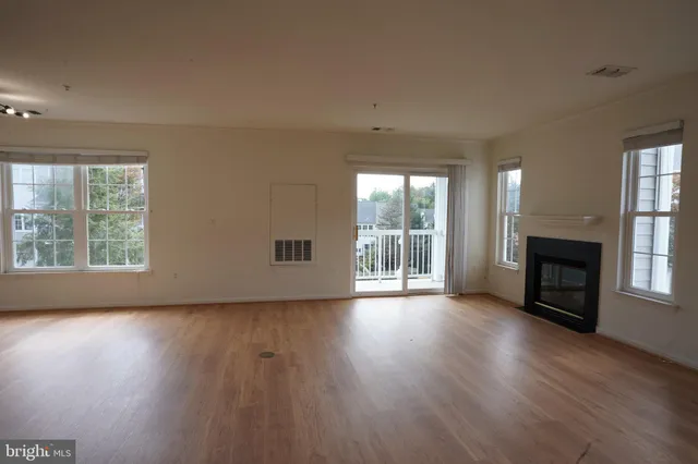 an empty room with wooden floor fireplace and windows