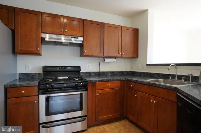 a kitchen with granite countertop stainless steel appliances a stove a sink and a microwave