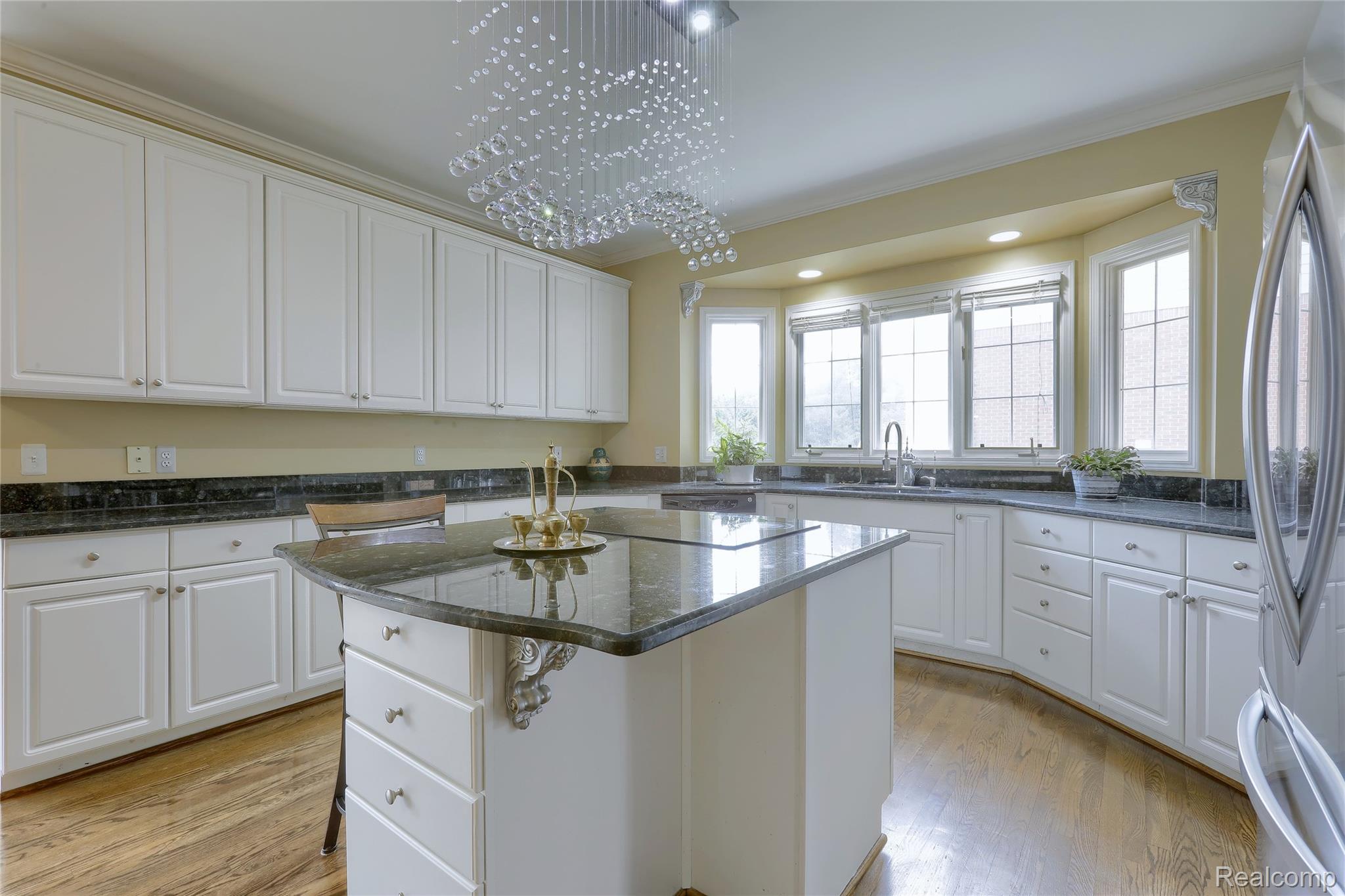 2007 Mapleridge Road Rochester, MI 48309 - Photo 15 of 45 Kitchen with dark stone counters, freestanding refrigerator, a kitchen island, white cabinetry, and crown molding
